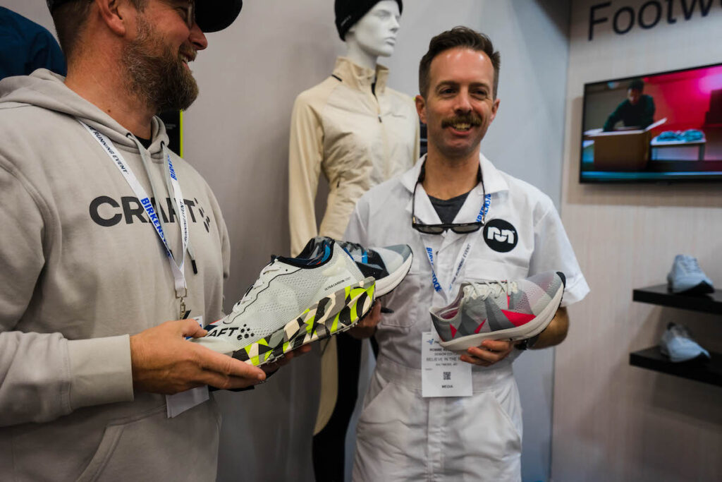 man in a white mechanic suit holding a shoe and smiling