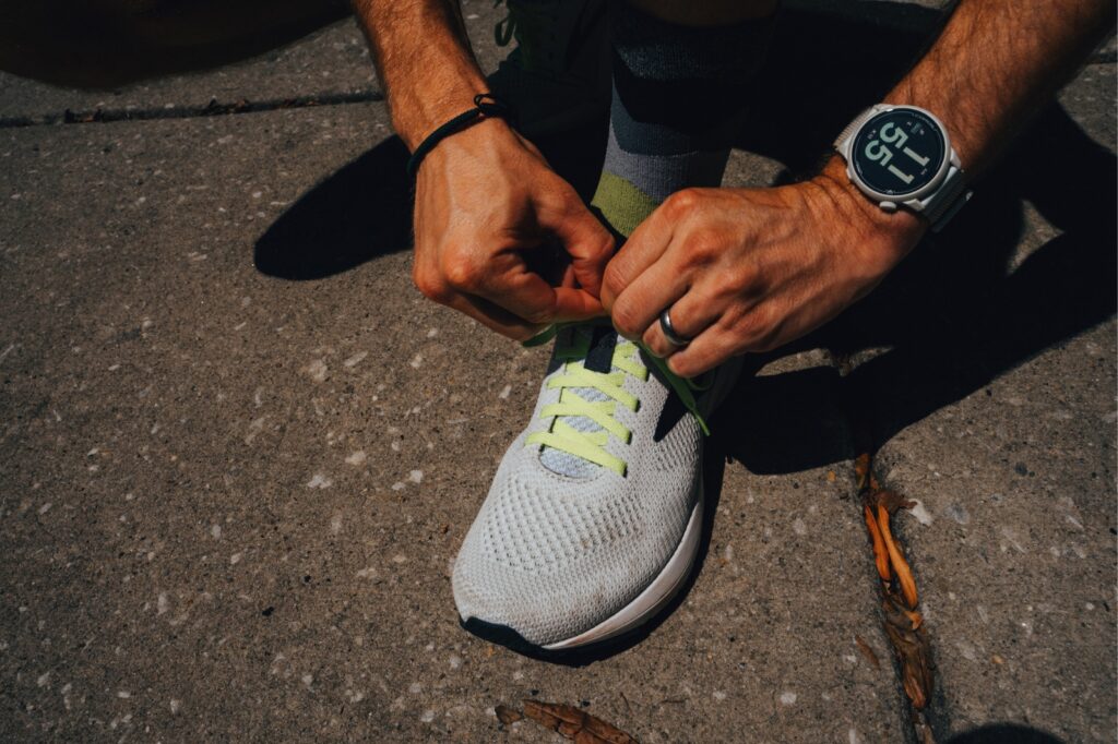 tying a running shoe on a sidewalk