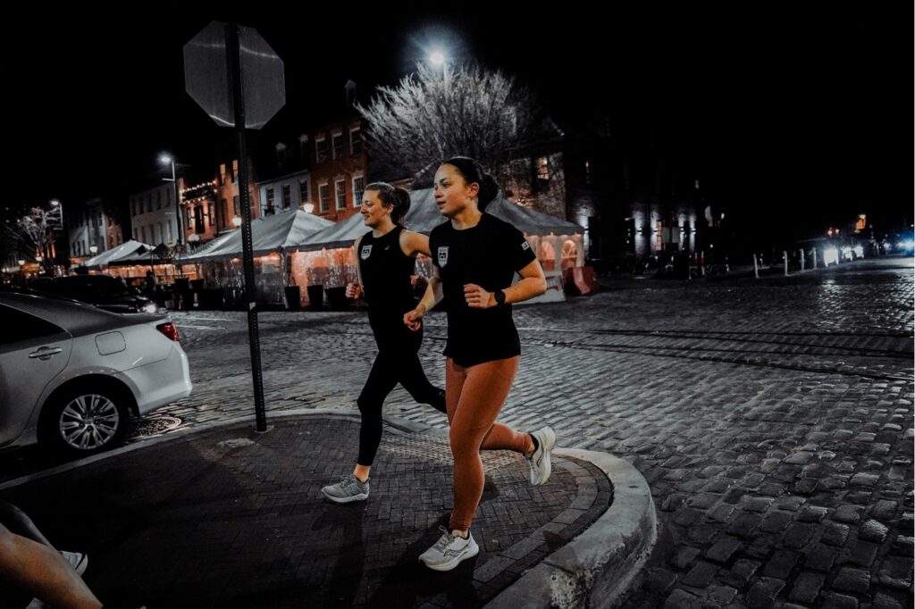 two women running at night on cobblestone streets